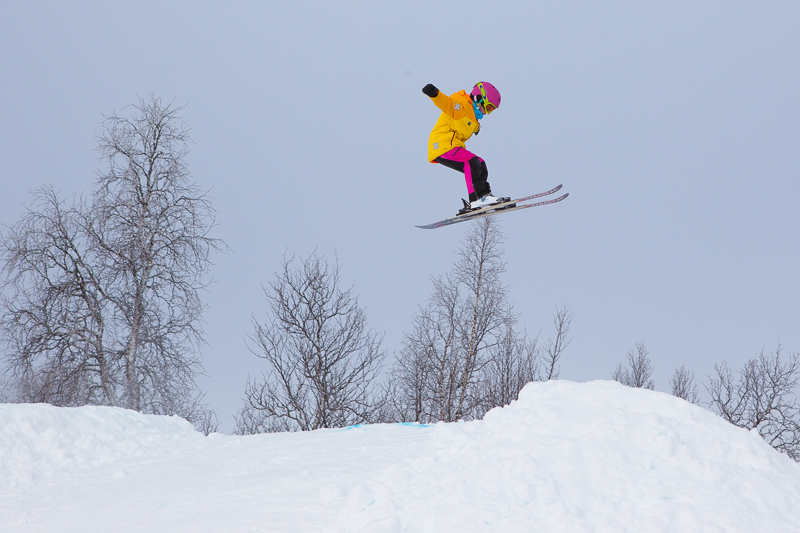 Ett barn i färgglada kläder som hoppar med skidor i slalombacken i Klimpfjäll